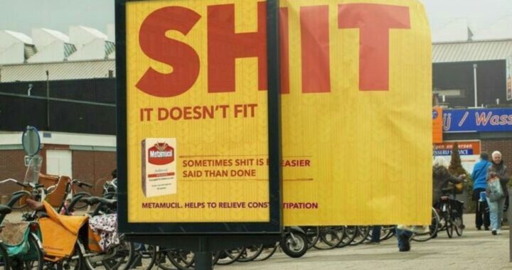 A yellow Metamucil billboard on a Dutch street, its oversized headline making a crude joke about the product not fitting.